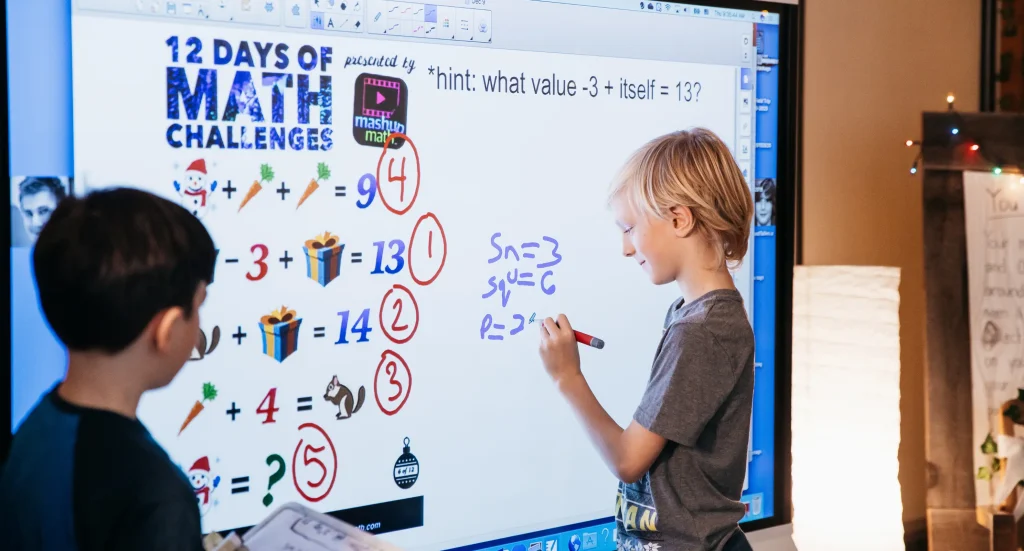 Children in a classroom using a SMART whiteboard to learn math